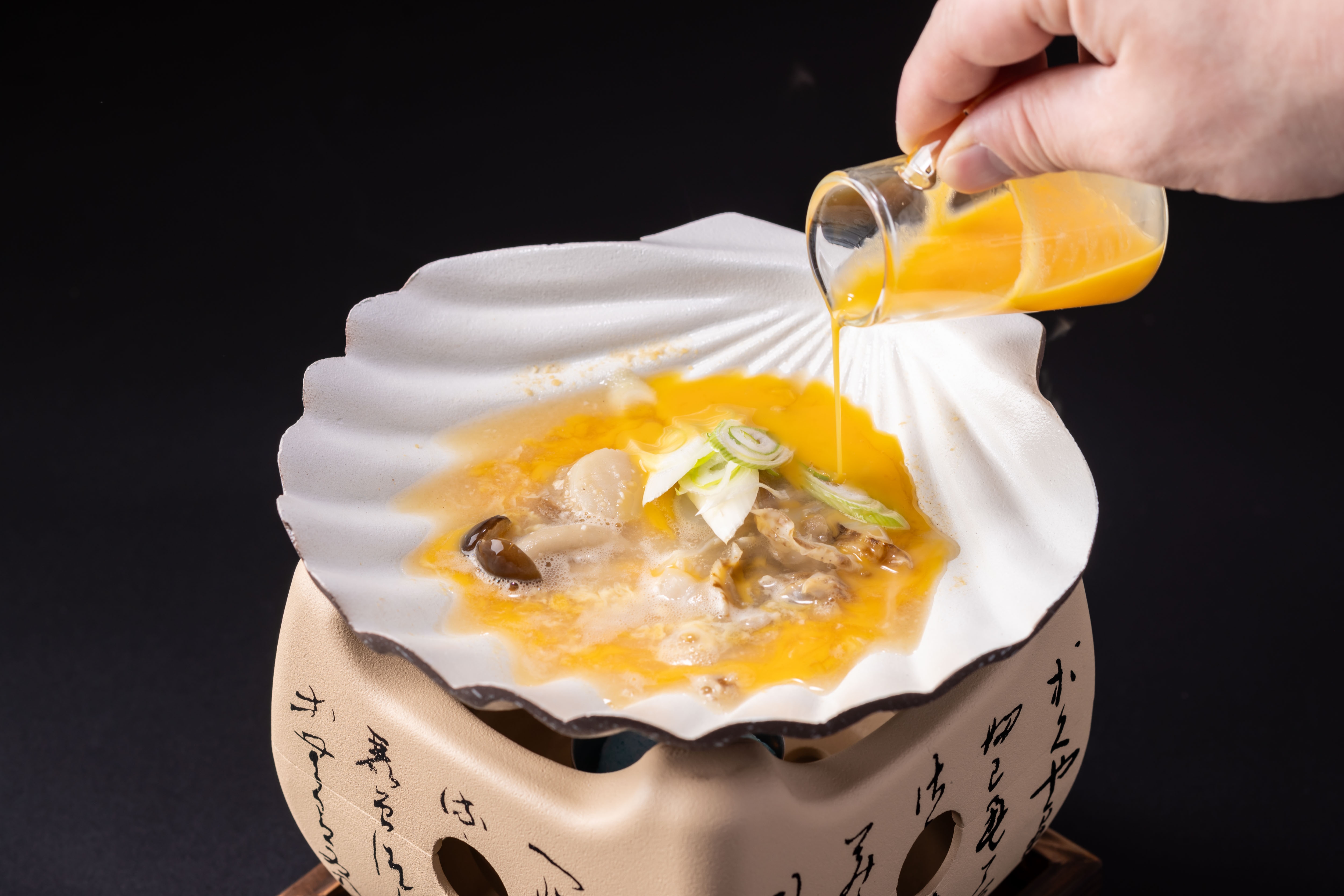 リッチモンドホテル青森の朝食で提供される青森郷土料理「貝焼き味噌」。ホタテの貝殻で卵と出汁を煮込んでいる様子